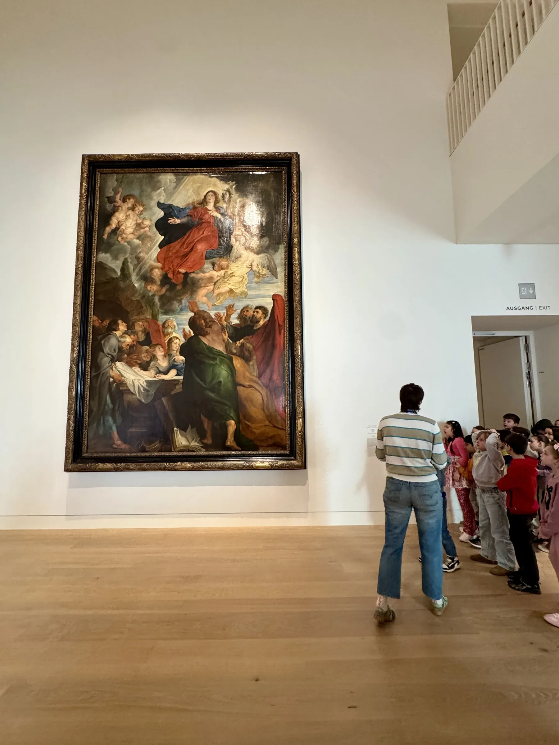 Großes religiöses Gemälde an weißer Museumswand links, rechts Erwachsener mit Gruppe Kindern blickt darauf