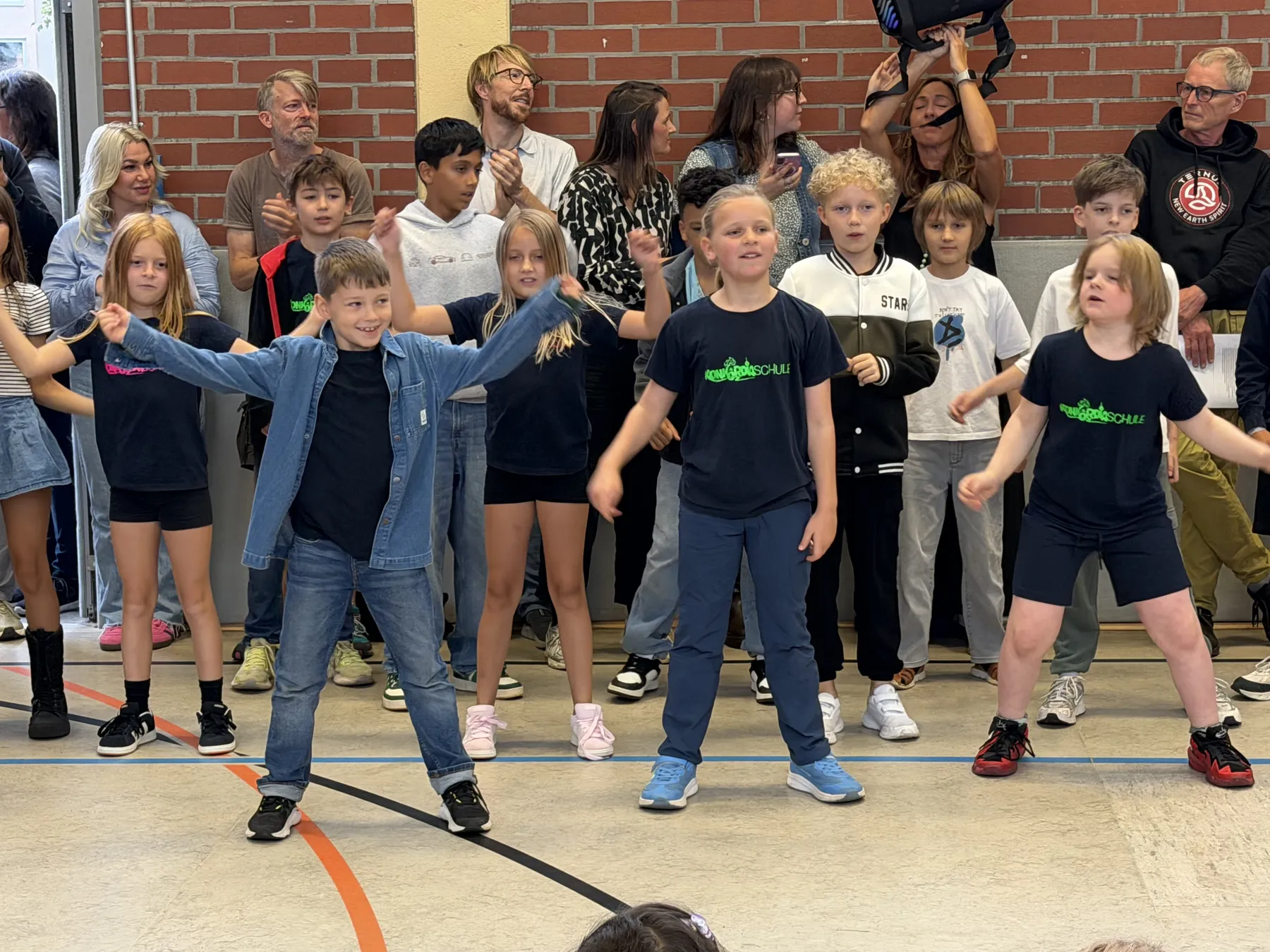Kindergruppe beim Auftritt in Turnhalle vor Zuschauern, tanzend und singend