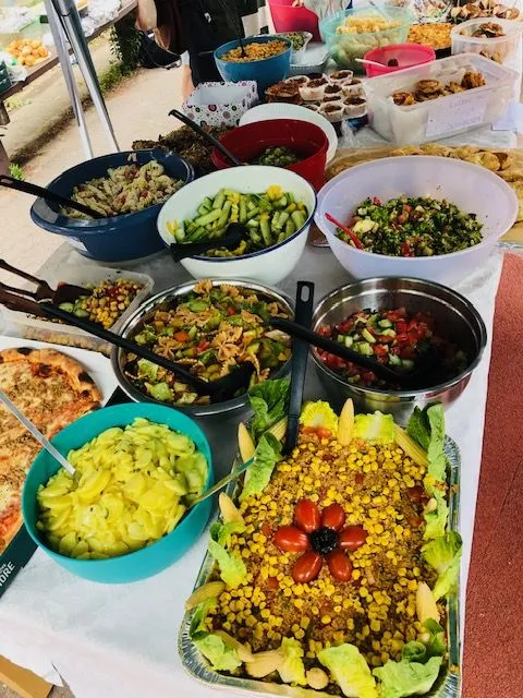 Buffet mit vielen Schüsseln voller Salate, geschnittenem Gemüse, Mais, Kirschtomaten und Salatblättern