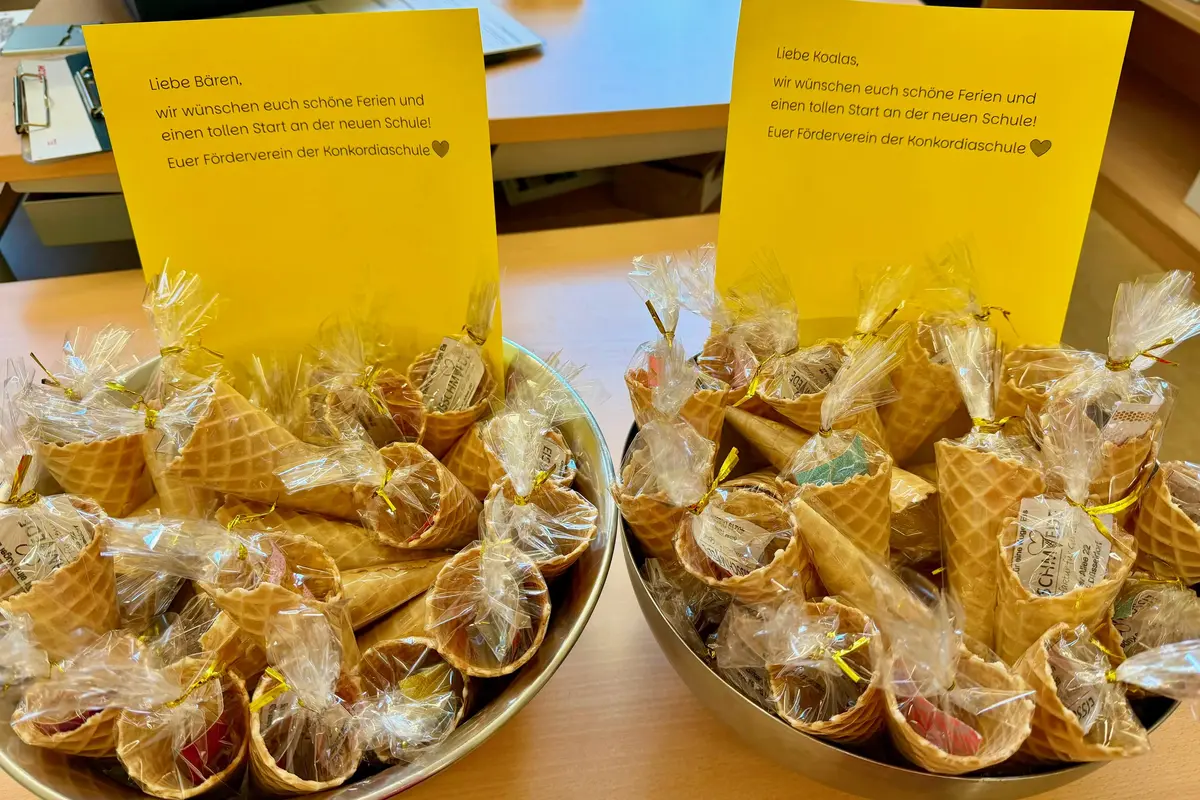 Zwei Schüsseln mit in Klarsichtfolie verpackten Waffelbechern voller Süßigkeiten und zwei gelbe Grußkarten auf Tisch