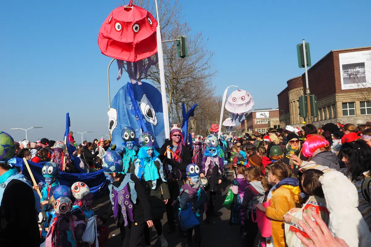 Menschen in bunten Quallen‑ und Oktopus‑Kostümen mit großen schwebenden Quallenballons bei Parade